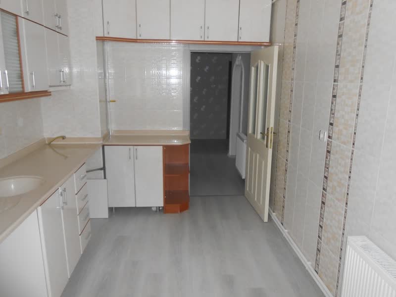 Beyaz dolaplı, parke zeminli boş mutfak